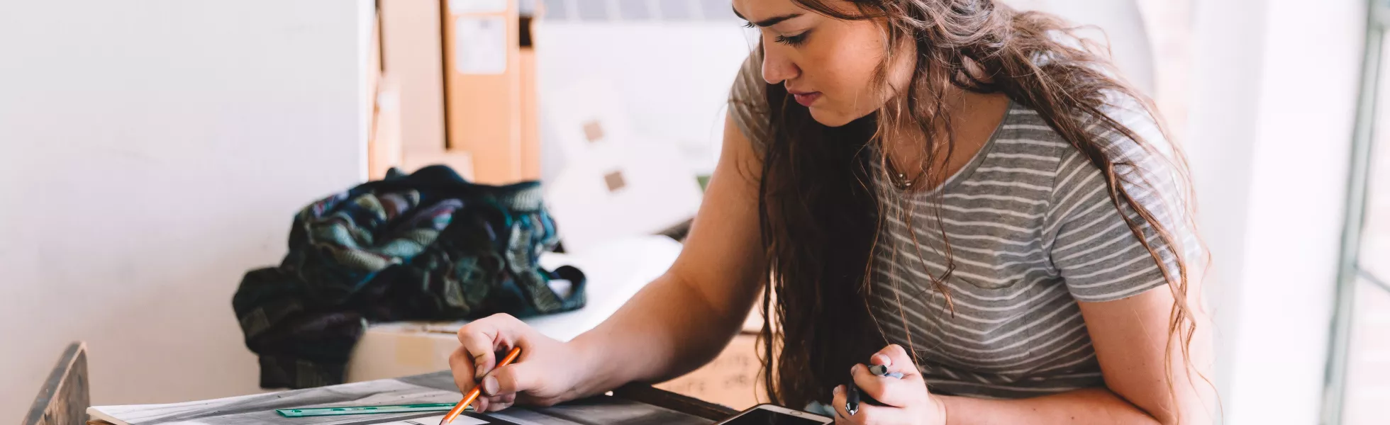 Student drawing on a large drawing pad in an art studio setting.