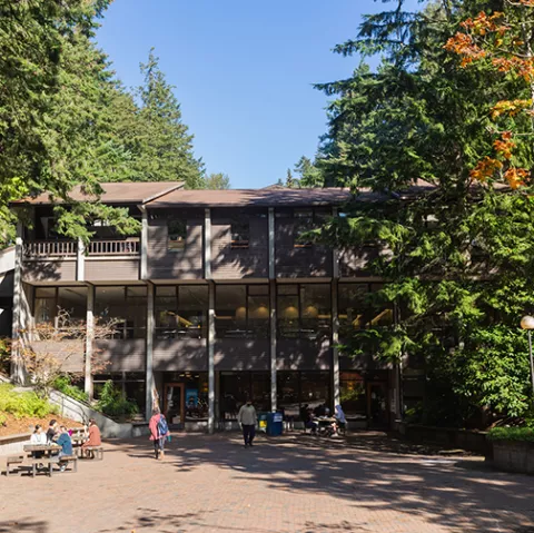 Fairhaven Academic, a three story wood building surrounded by trees overlooking a brick plaza.