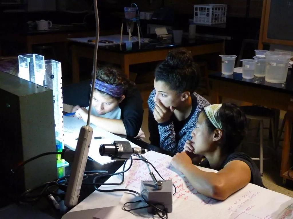 Young students observing samples in a dark room